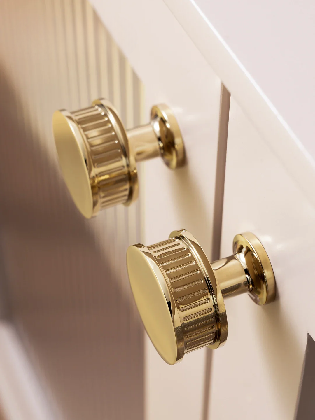 Gold cabinet knobs on a white wooden surface