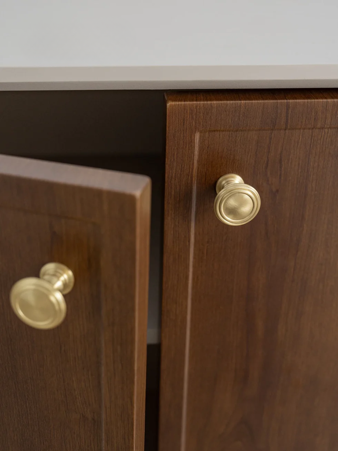 Wooden cabinet with gold handles on a neutral background