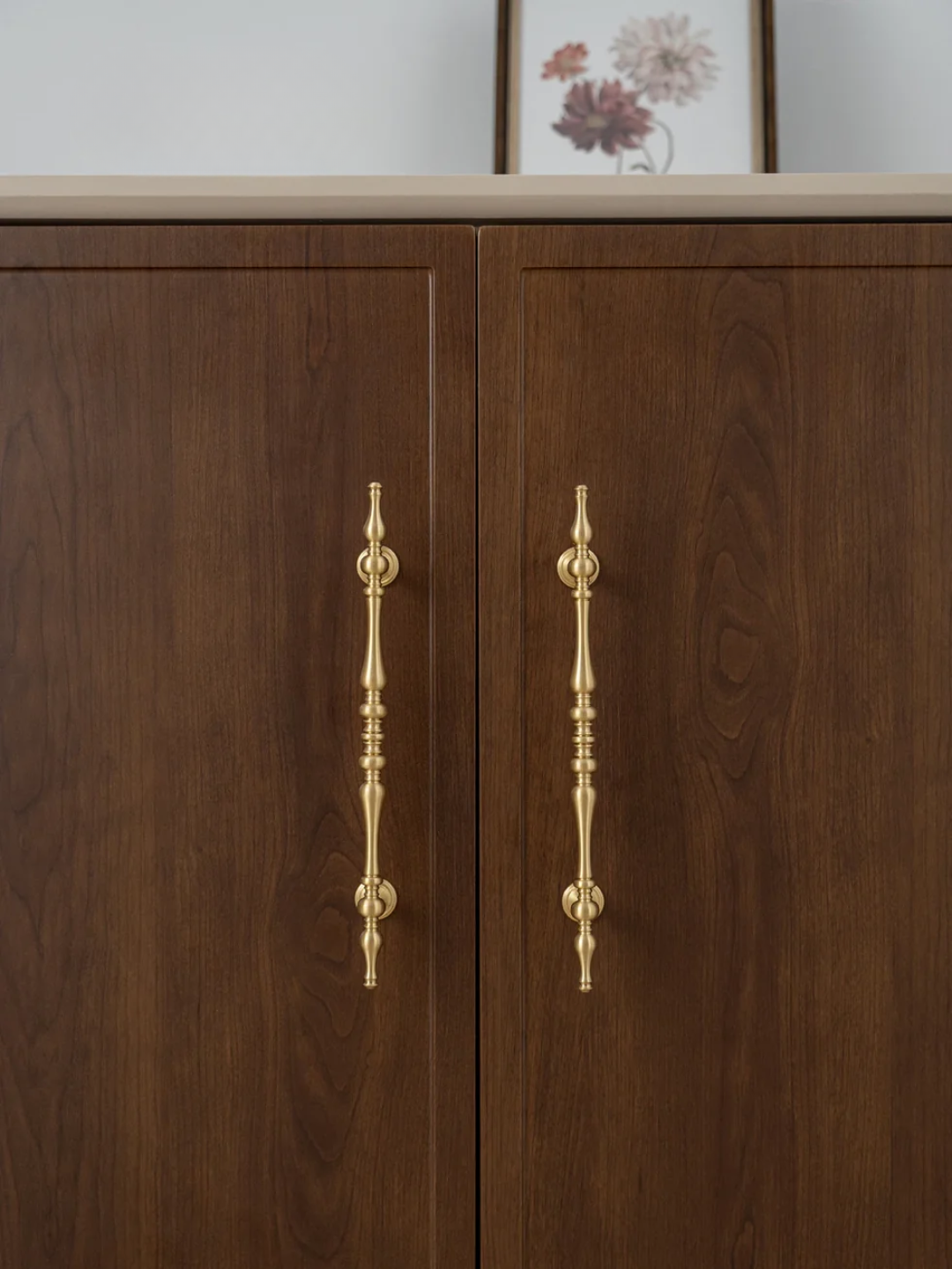 Wooden cabinet with gold handles and a framed picture in the background