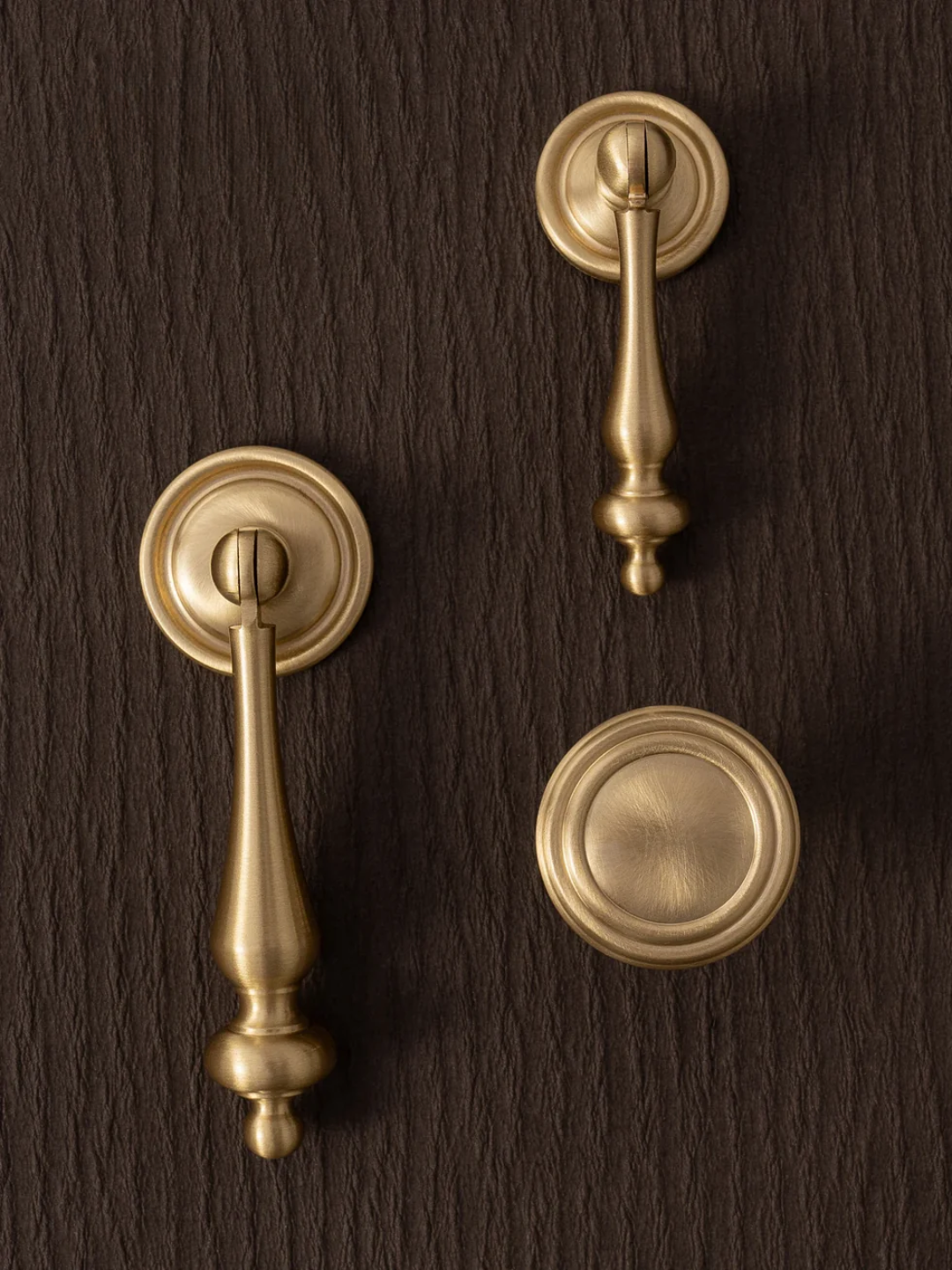 Set of brass door handles on a dark wooden background