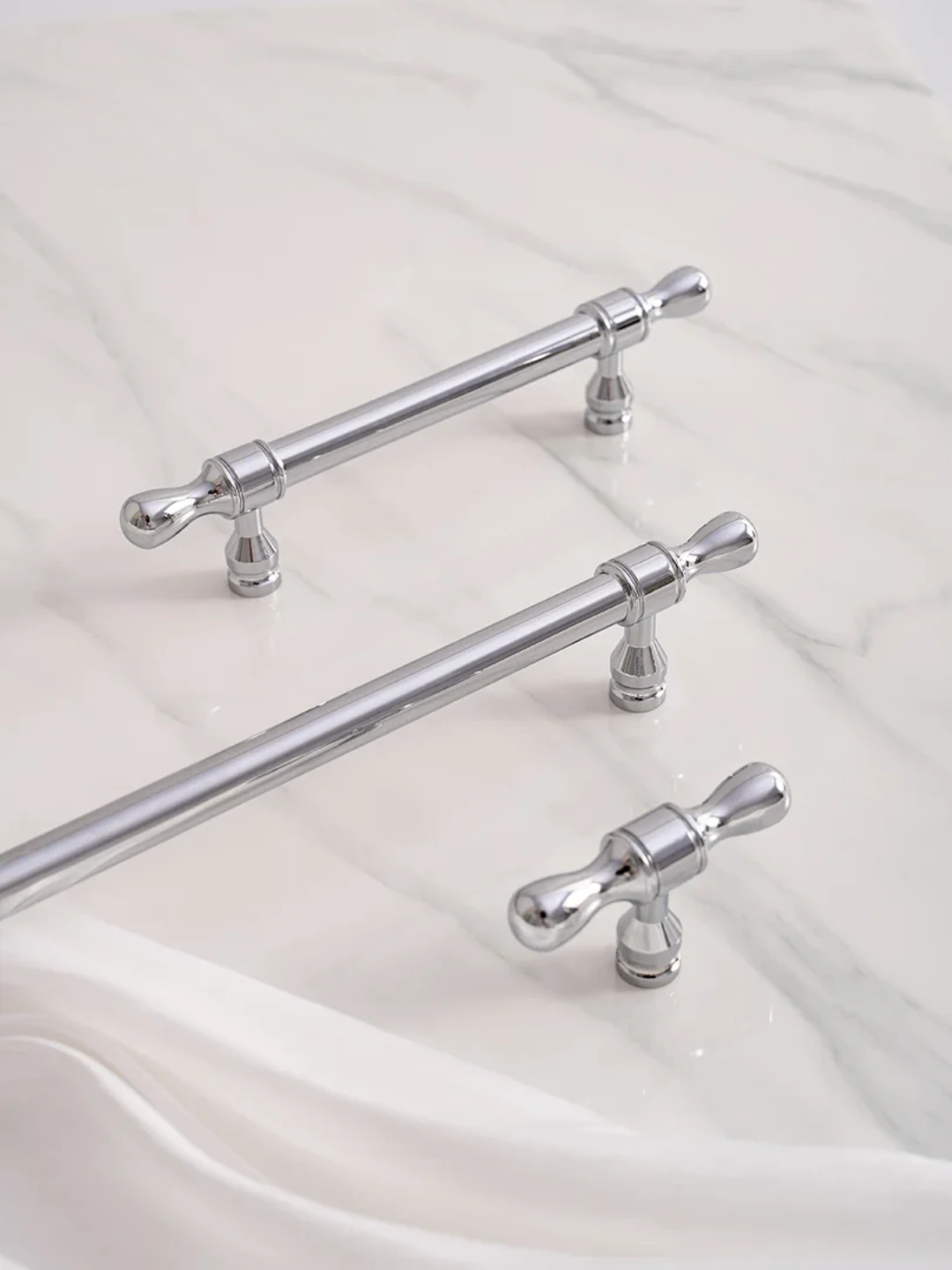 Set of silver handles on a white fabric background