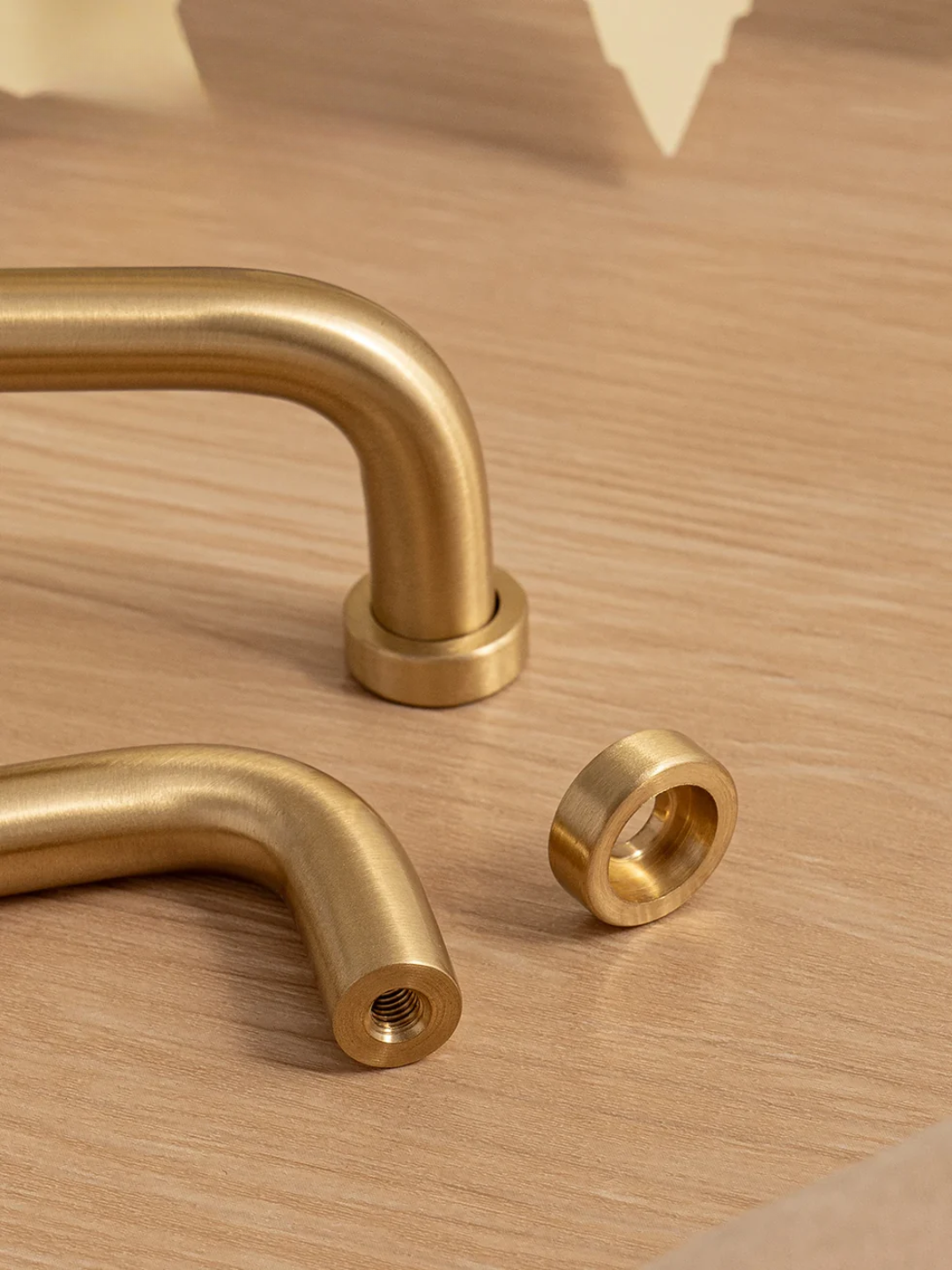Two gold handles and a matching gold washer on a wooden surface