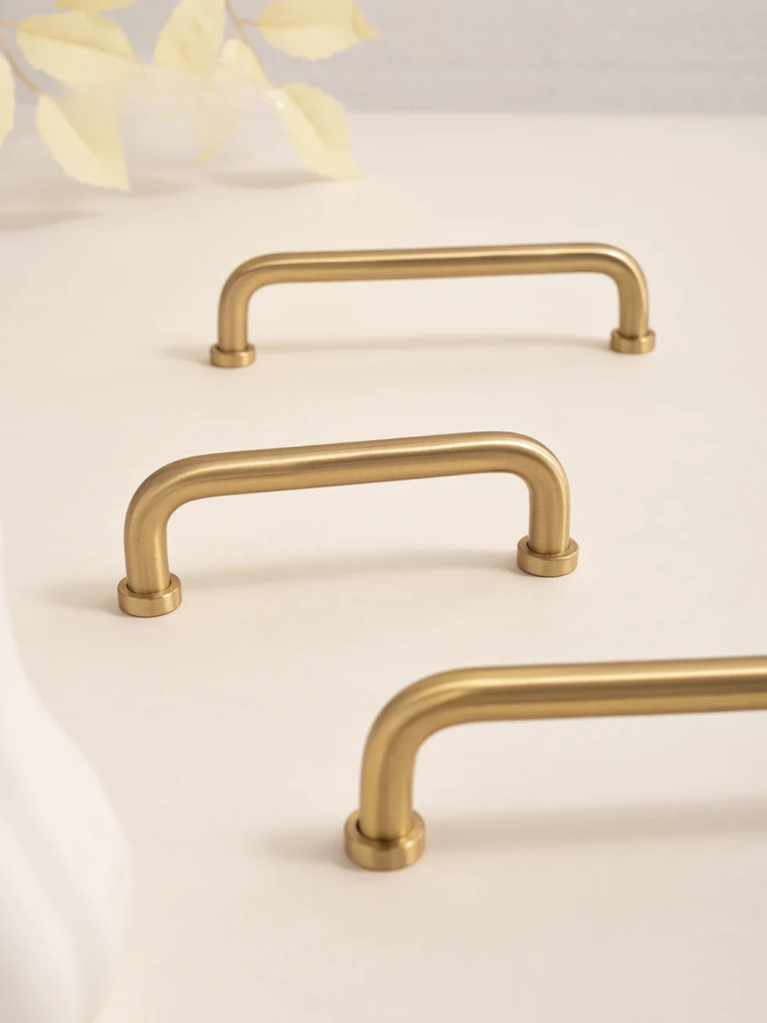 Three gold cabinet handles on a light beige background