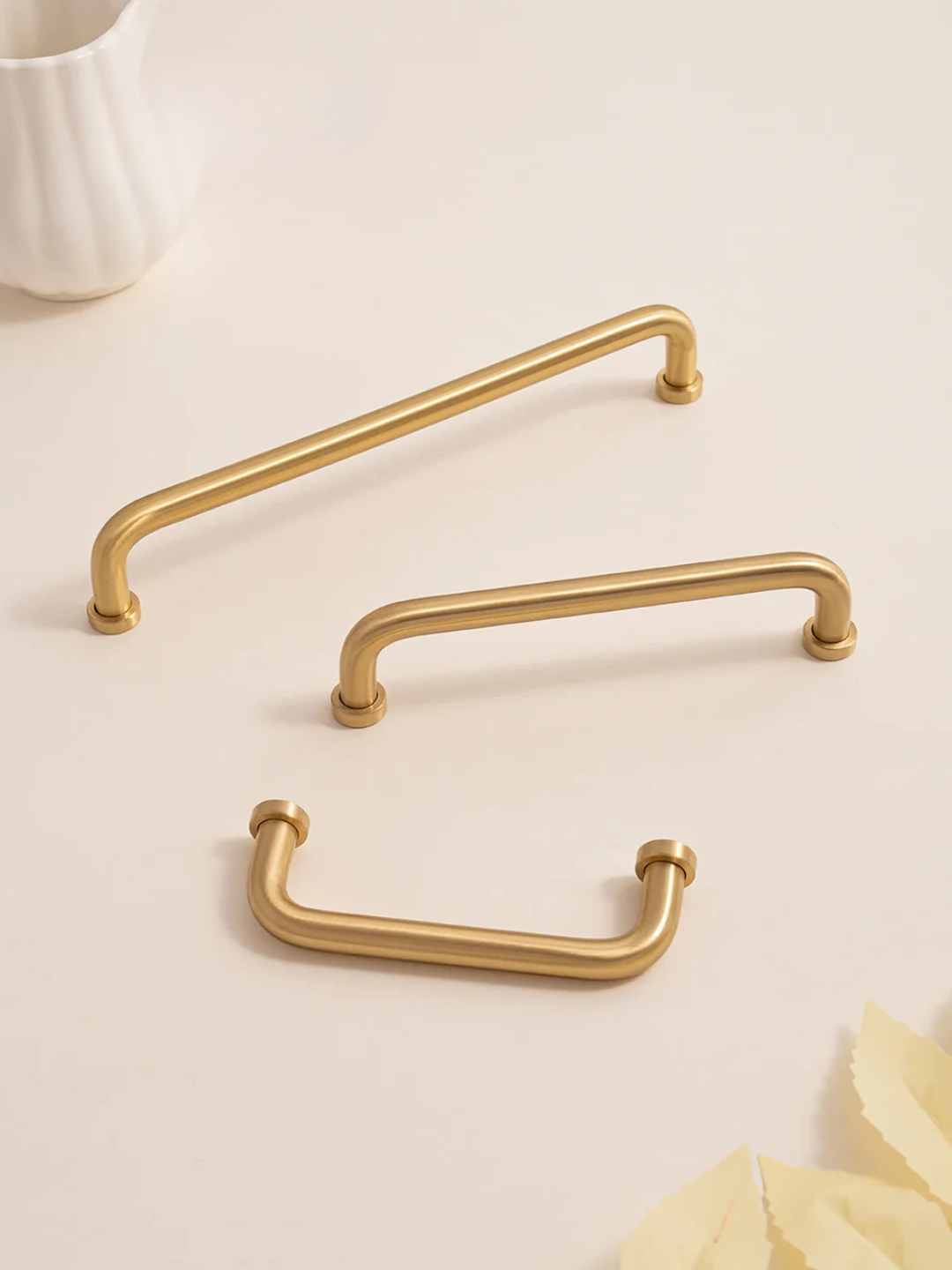Three gold cabinet handles on a light beige background