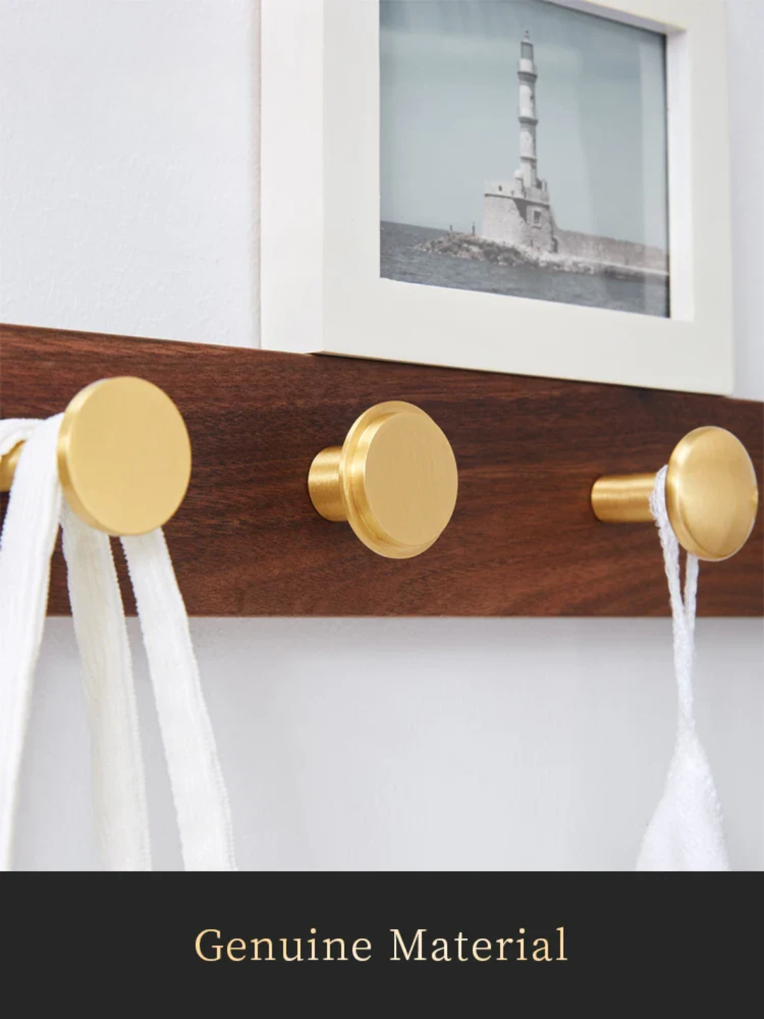 Wooden coat rack with gold hooks holding white fabric, framed picture of a lighthouse in the background.