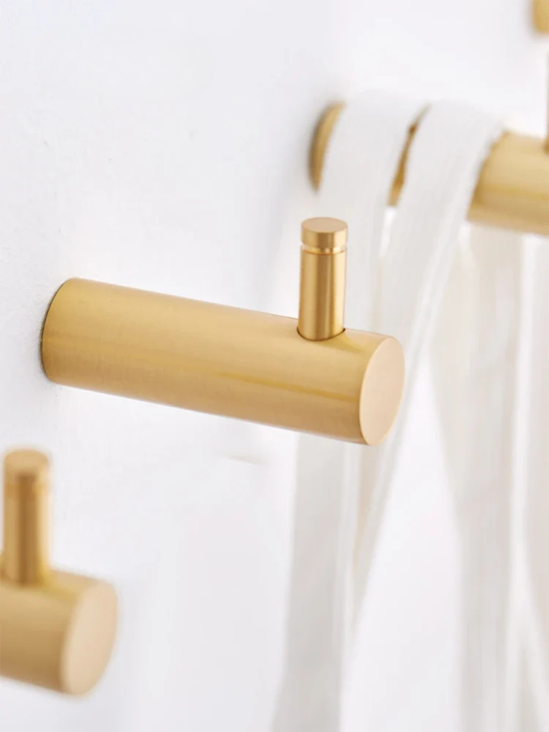 Gold wall hooks on a white background