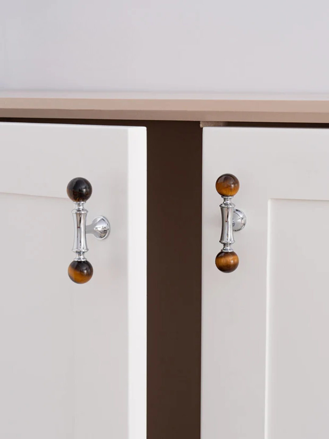 Close-up of a cabinet with decorative knobs on a neutral background
