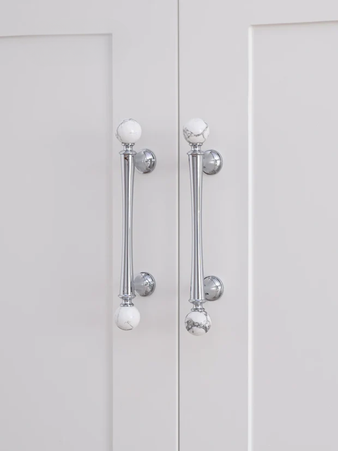 Close-up of a white cabinet with chrome handles on a white background