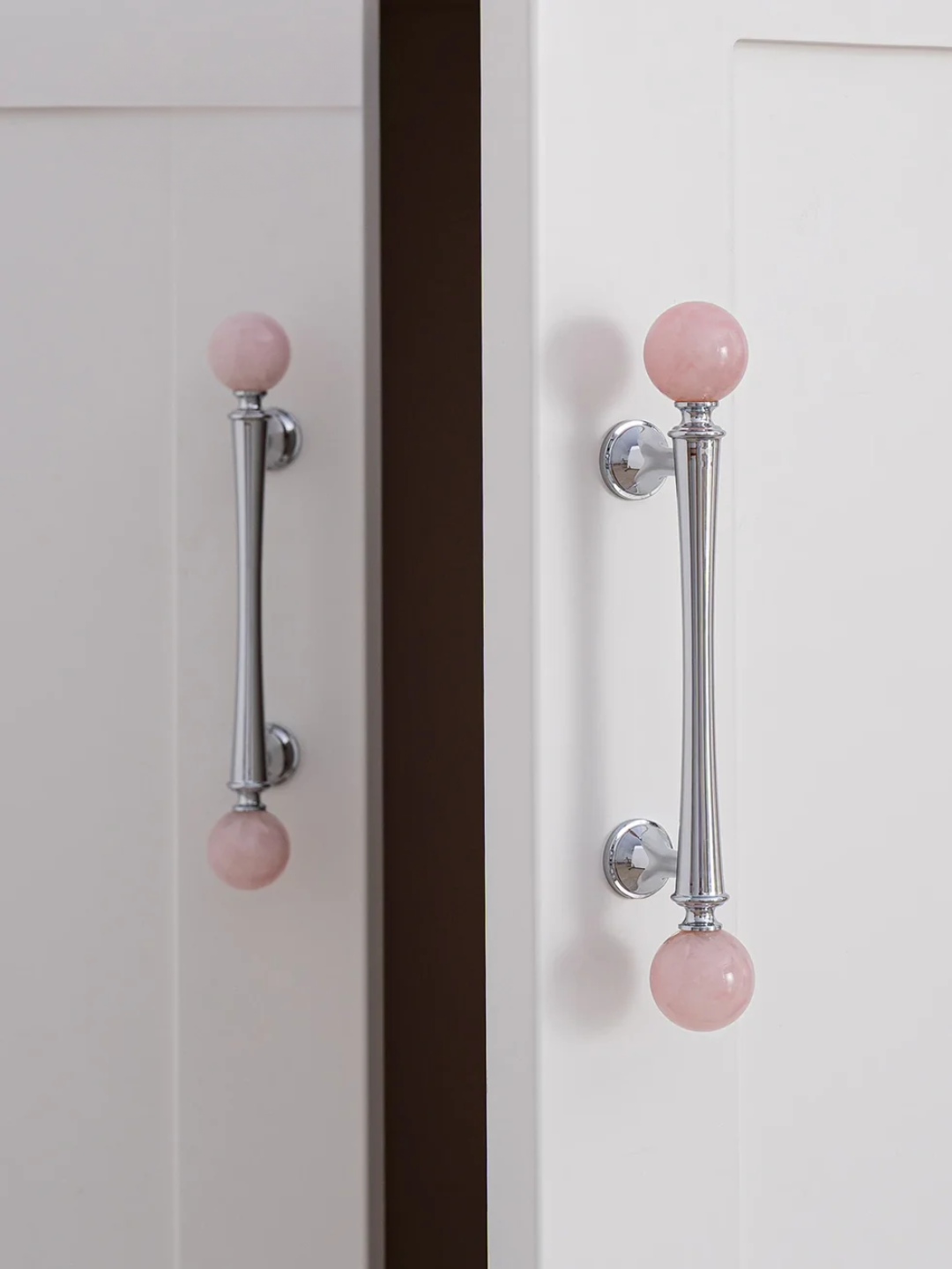 Cabinet doors with pink knobs on a neutral background