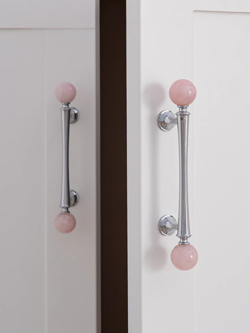 Cabinet doors with pink knobs on a neutral background