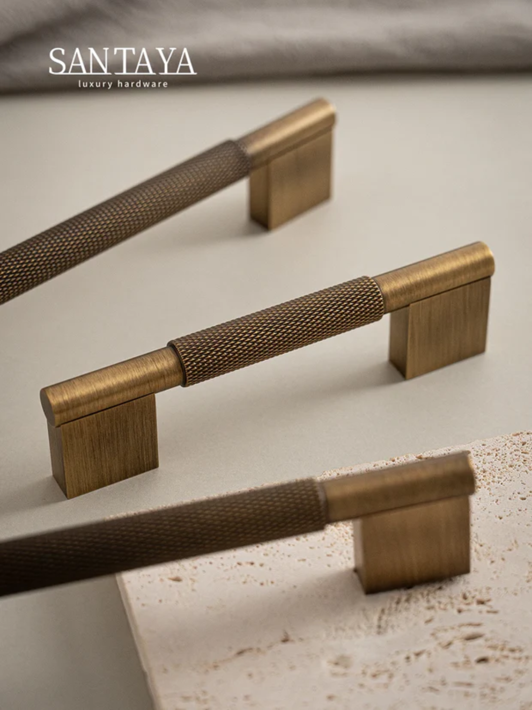 Brass cabinet handles on a textured surface with 'Santaya' branding.