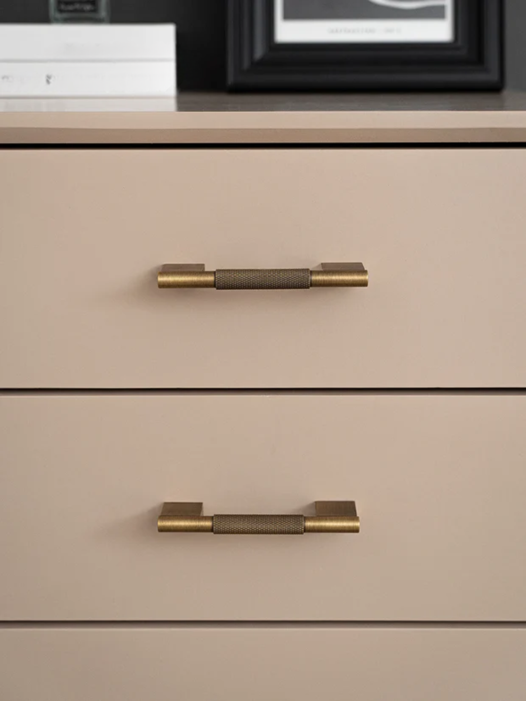 Beige dresser with gold handles on a neutral background