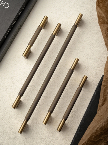 Set of five pens with bronze and black accents on a textured surface