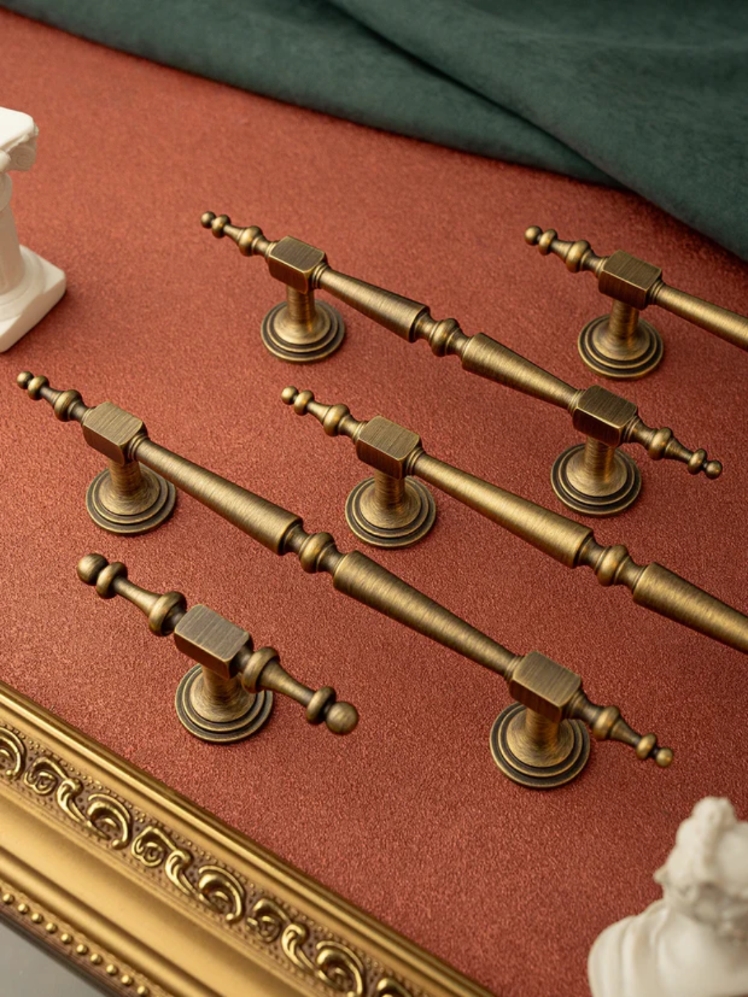 Set of gold cabinet handles on a red surface with decorative elements.