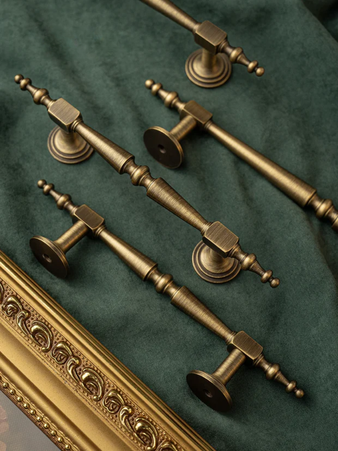 Set of ornate bronze door handles on a green fabric background