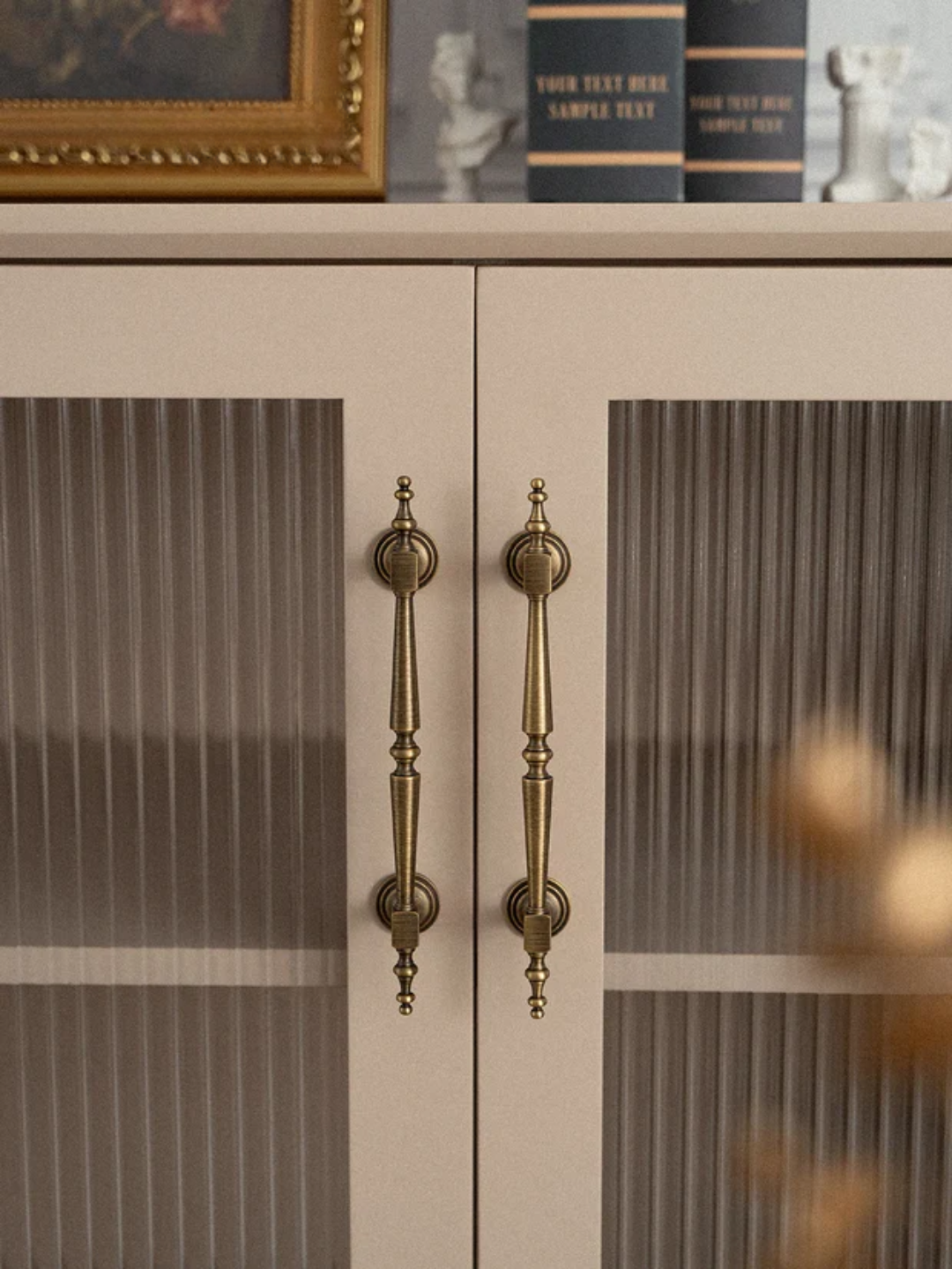 Cabinet with glass doors and brass handles on a neutral background