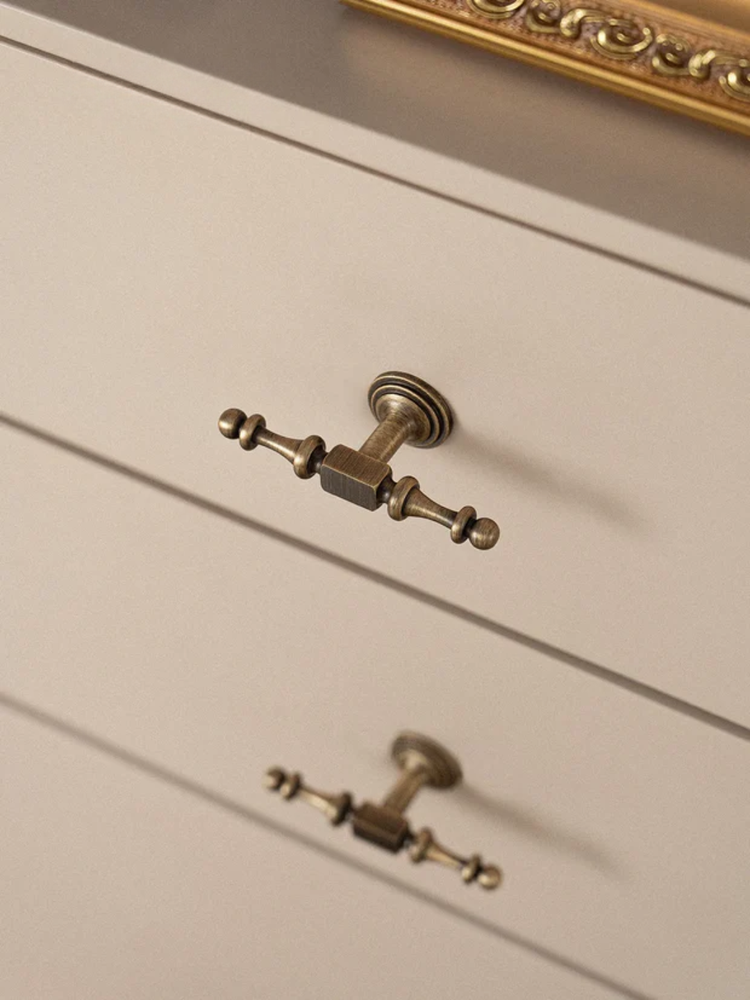 Close-up of a cabinet with decorative brass handles on a neutral background