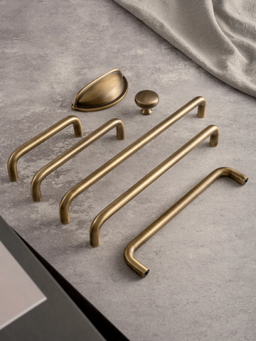 Set of gold cabinet handles and knobs on a gray surface with 'Santaya' branding.