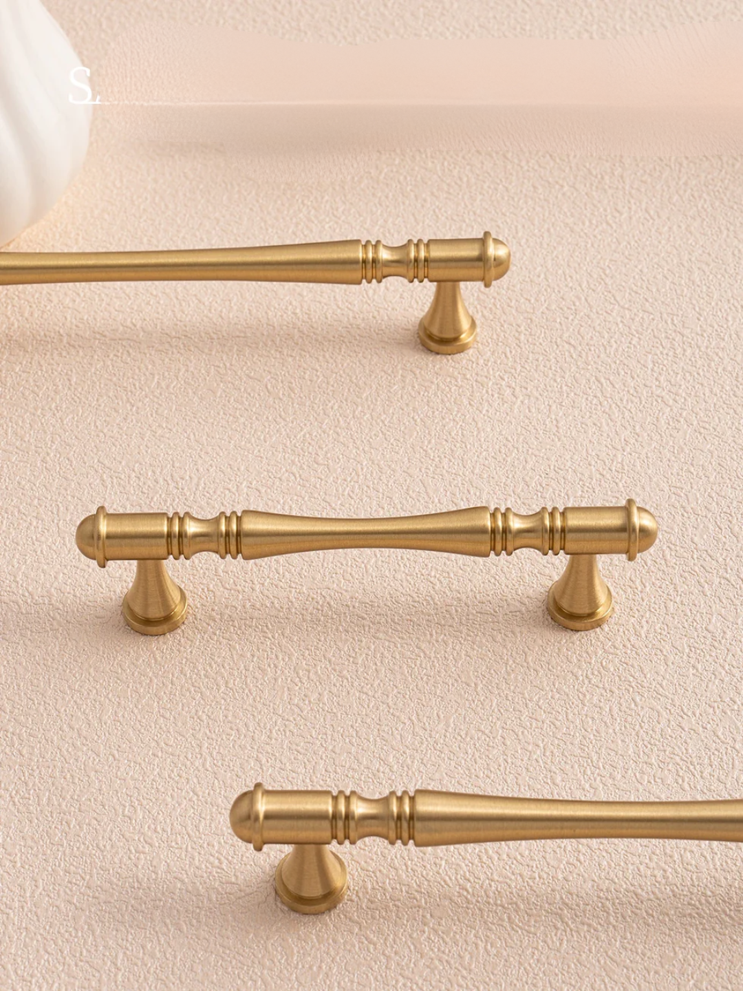 Gold cabinet handles on a beige surface