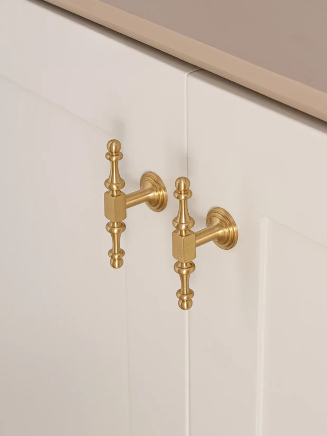 Gold faucet mounted on a white cabinet