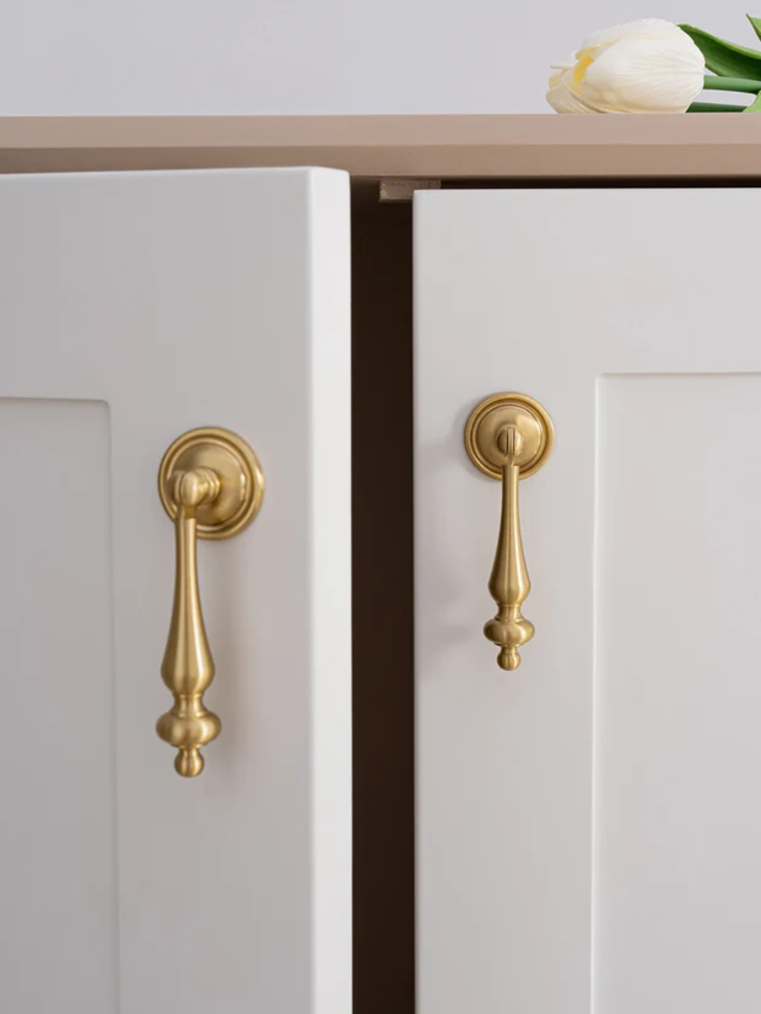 Close-up of white cabinets with gold handles on a light gray background