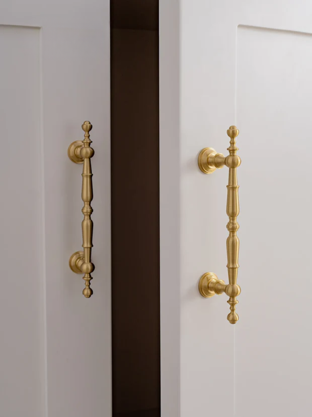 Close-up of a white cabinet with gold handles on a dark background