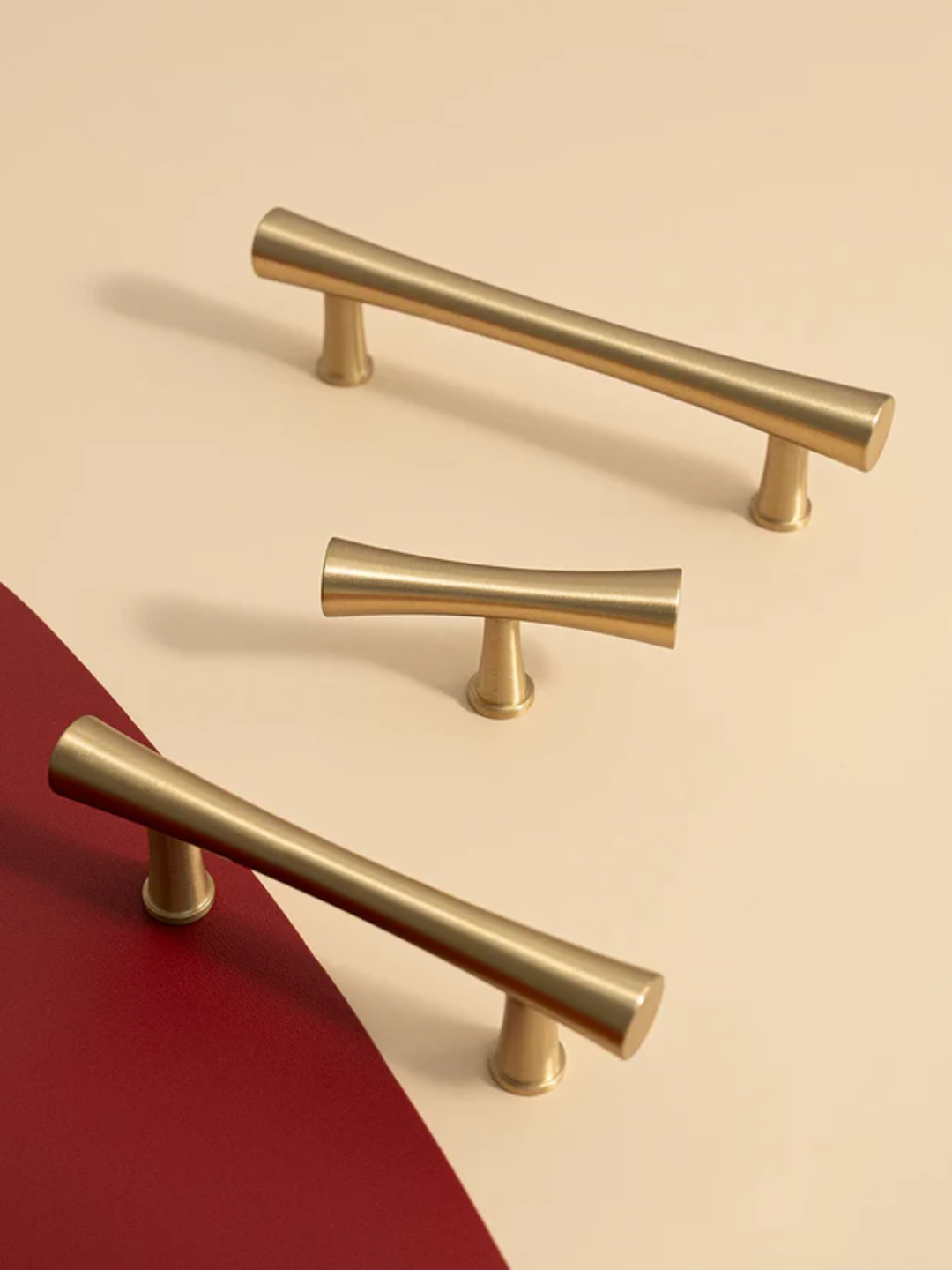 Set of gold cabinet handles on a beige and red background