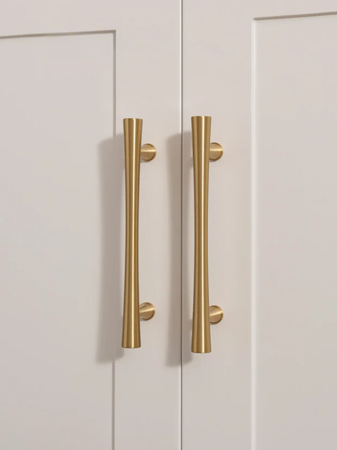 Pair of gold cabinet handles on a white door