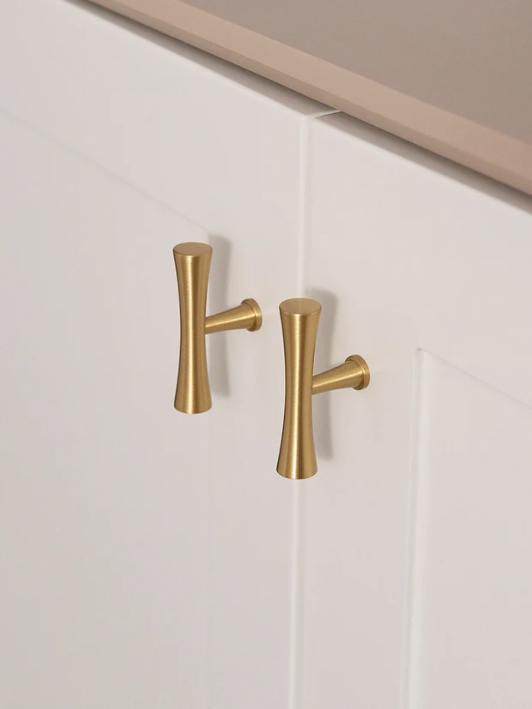 Gold cabinet handles on a white cabinet door