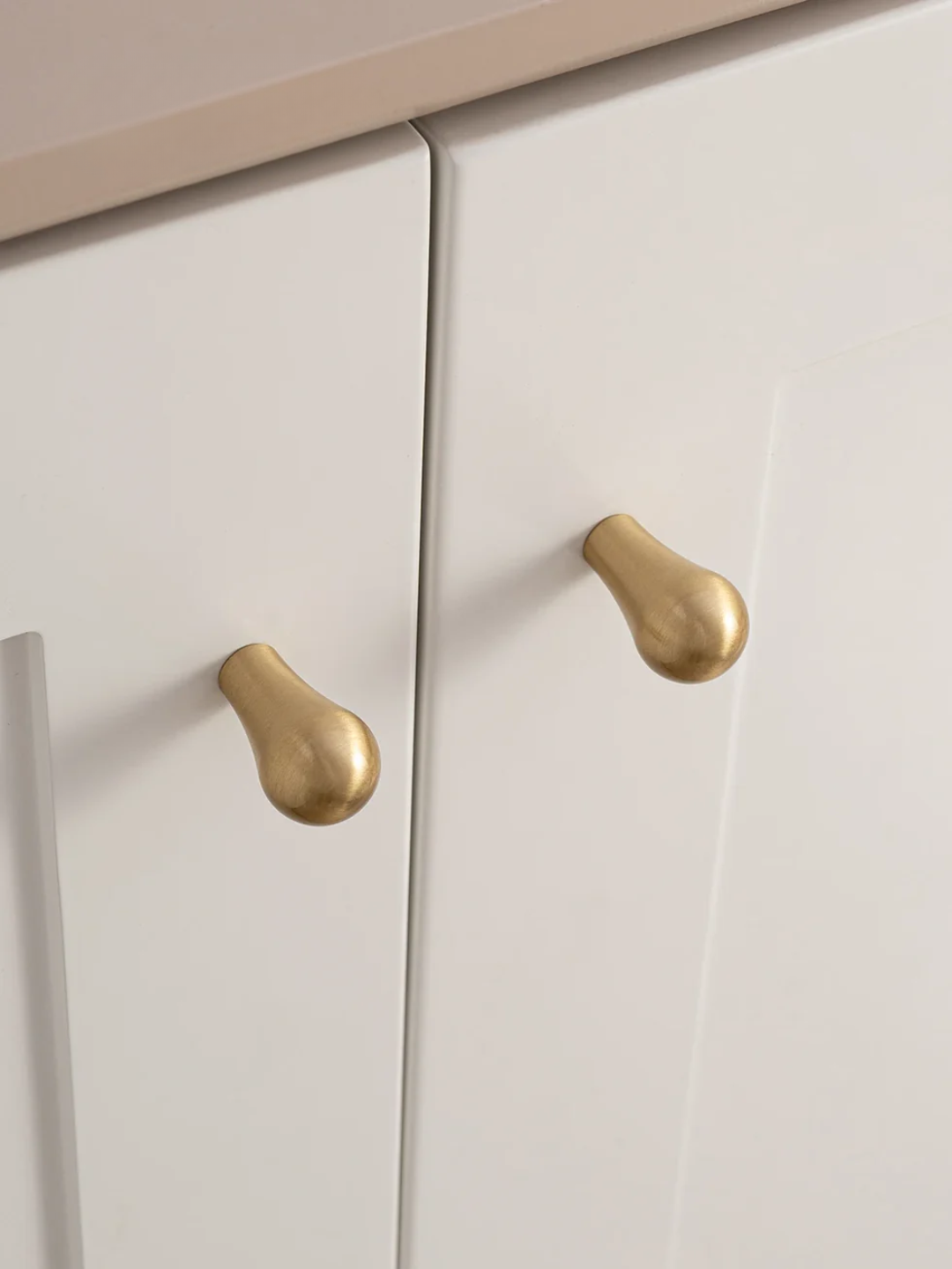 Close-up of white cabinet doors with gold handles