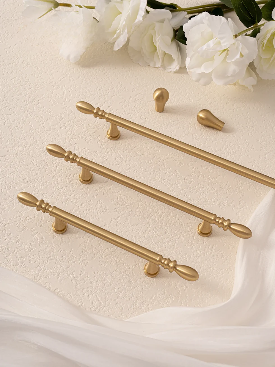 Set of gold cabinet handles on a light background with white flowers.
