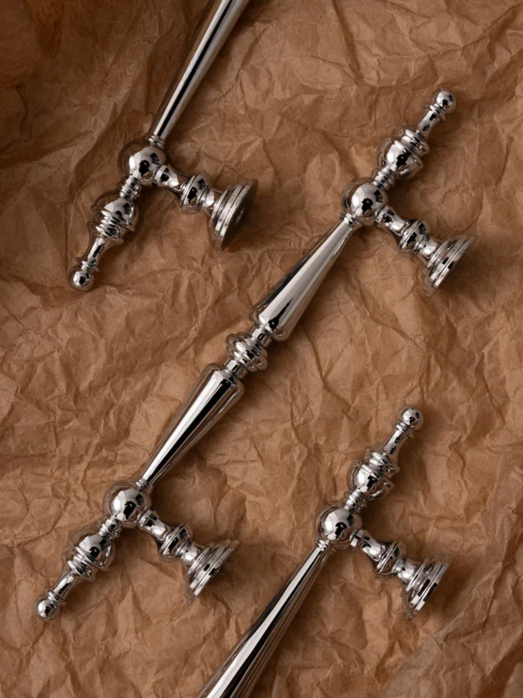 Three silver door handles on a crumpled brown paper background