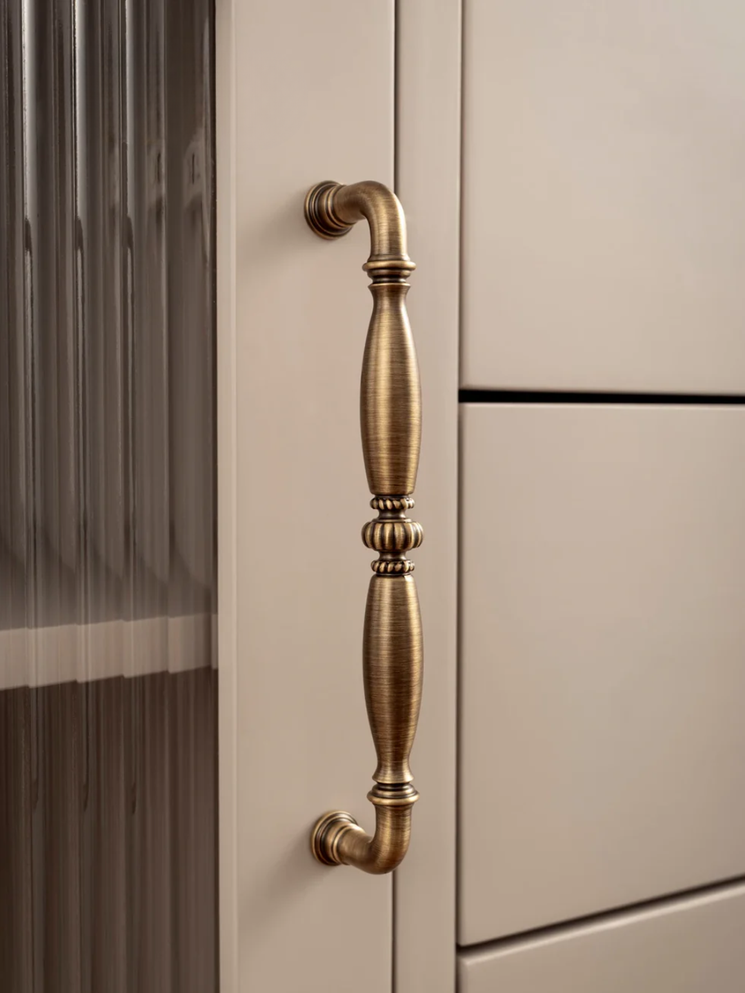 Close-up of a beige cabinet with a decorative brass handle