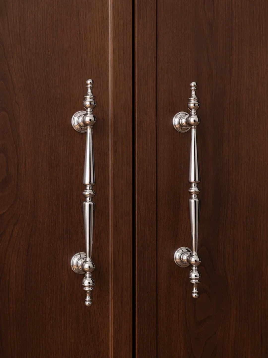 Pair of silver cabinet handles on a wooden door