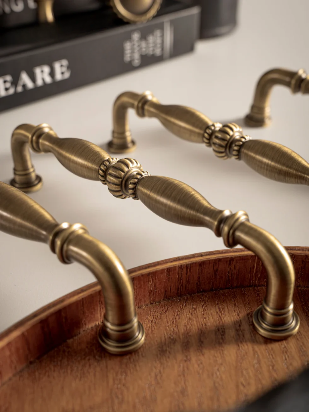 Close-up of ornate brass cabinet handles on a wooden surface with a blurred background.