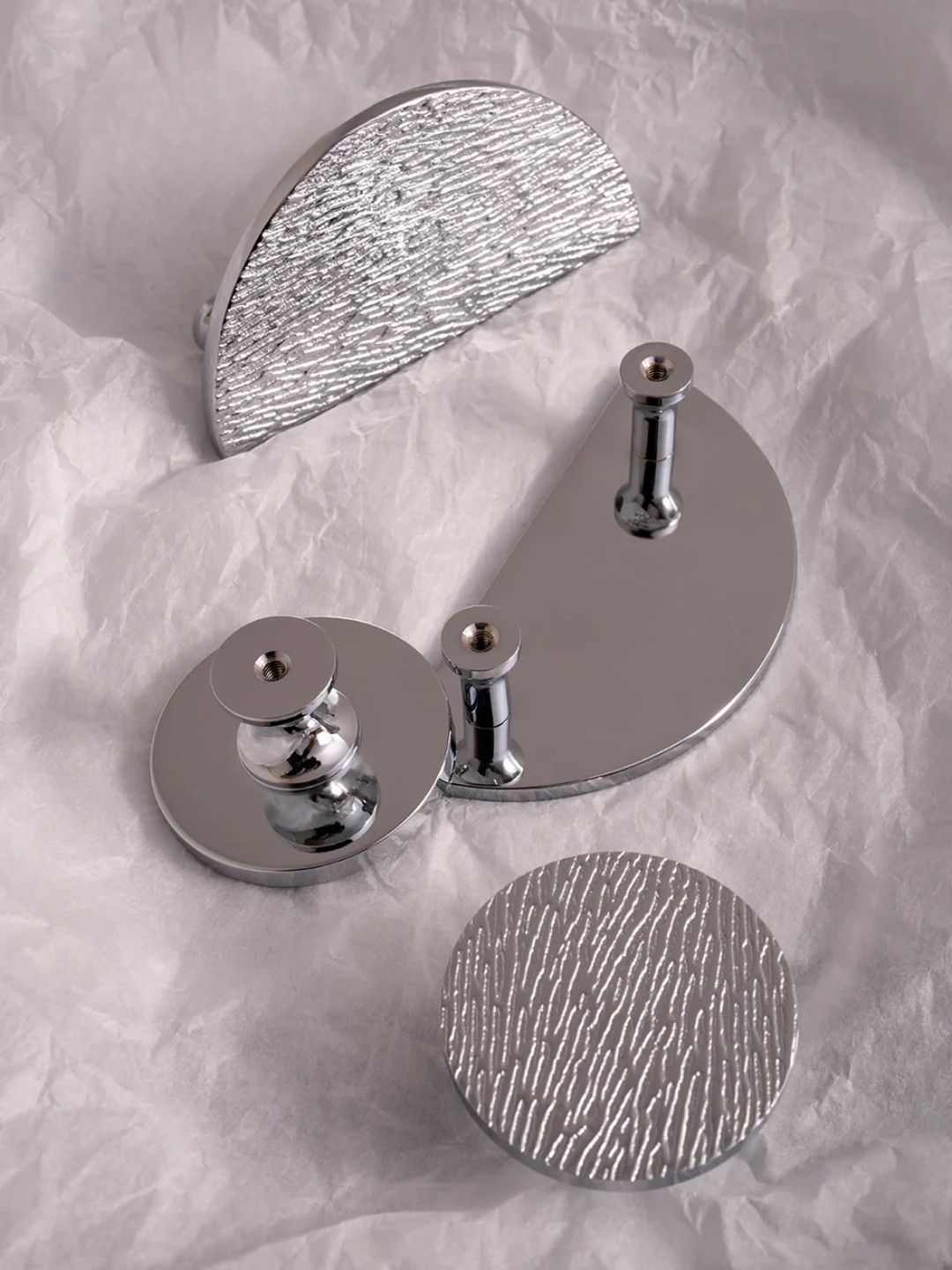 Set of silver wall hooks on a textured white background