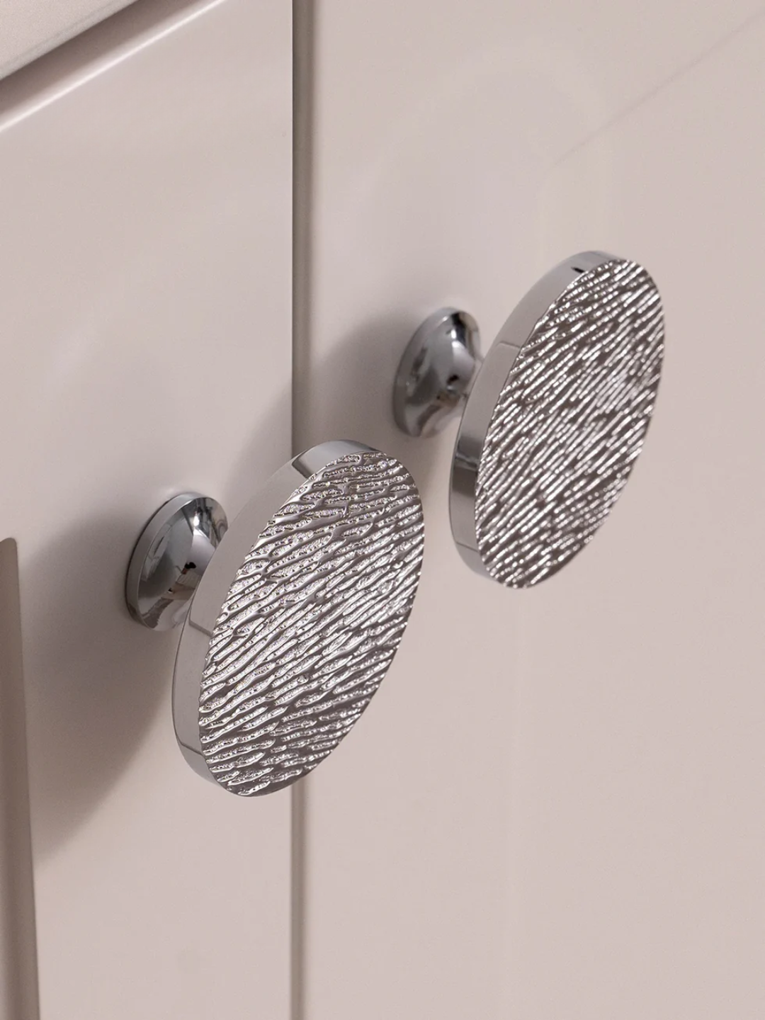 Textured silver cabinet handles on a light-colored cabinet door
