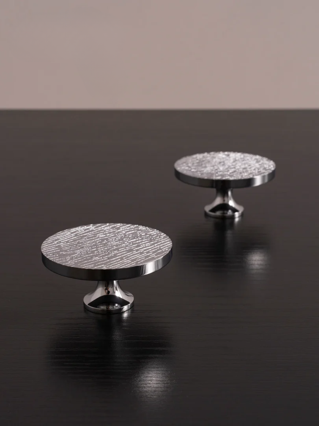 Two round metallic knobs on a dark surface with a neutral background