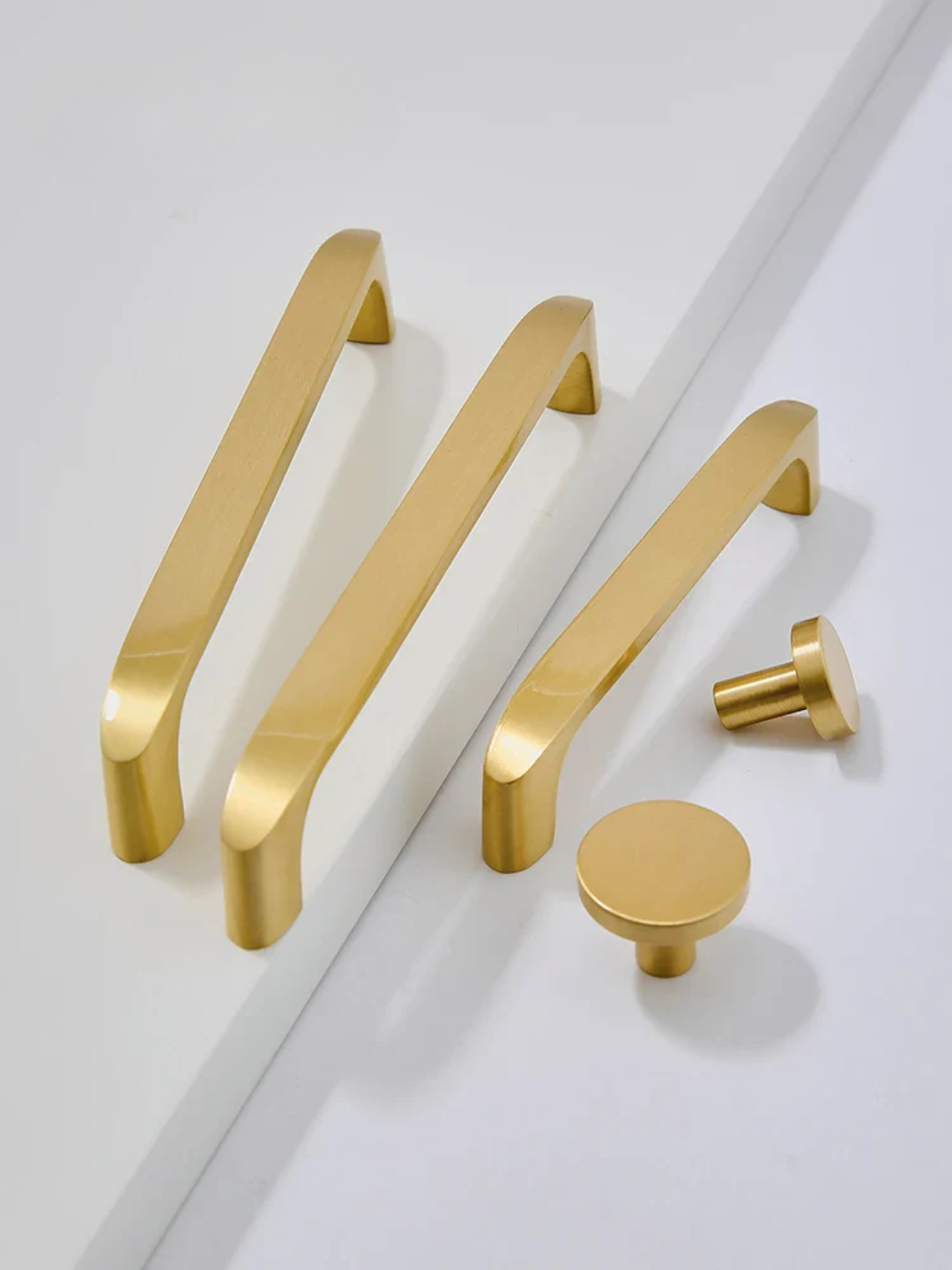 Set of gold cabinet handles and knobs on a white background