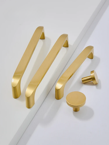 Set of gold cabinet handles and knobs on a white background