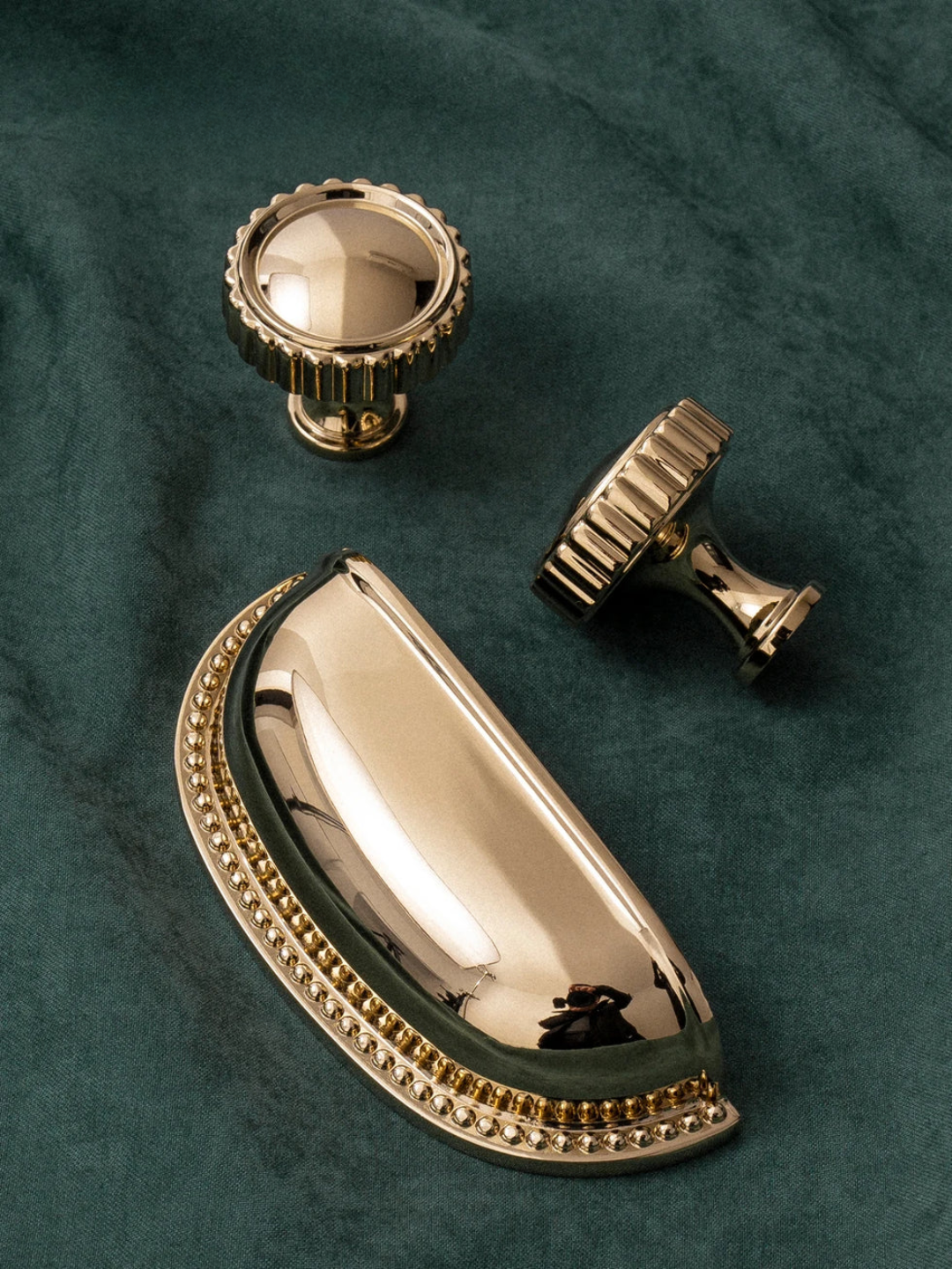 Gold cabinet knobs on a green fabric background