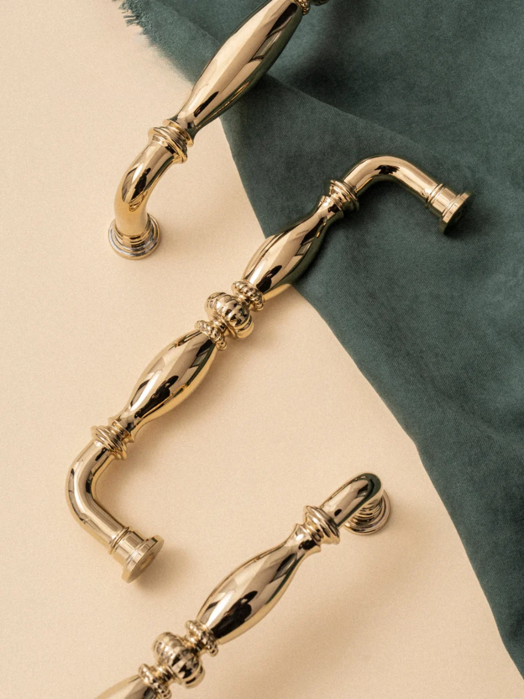 Gold cabinet handles on a beige and green fabric background