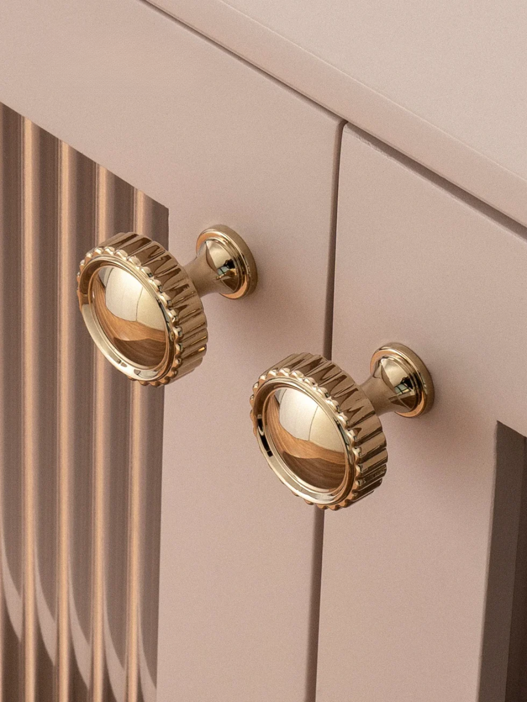 Gold cabinet knobs on a light pink cabinet