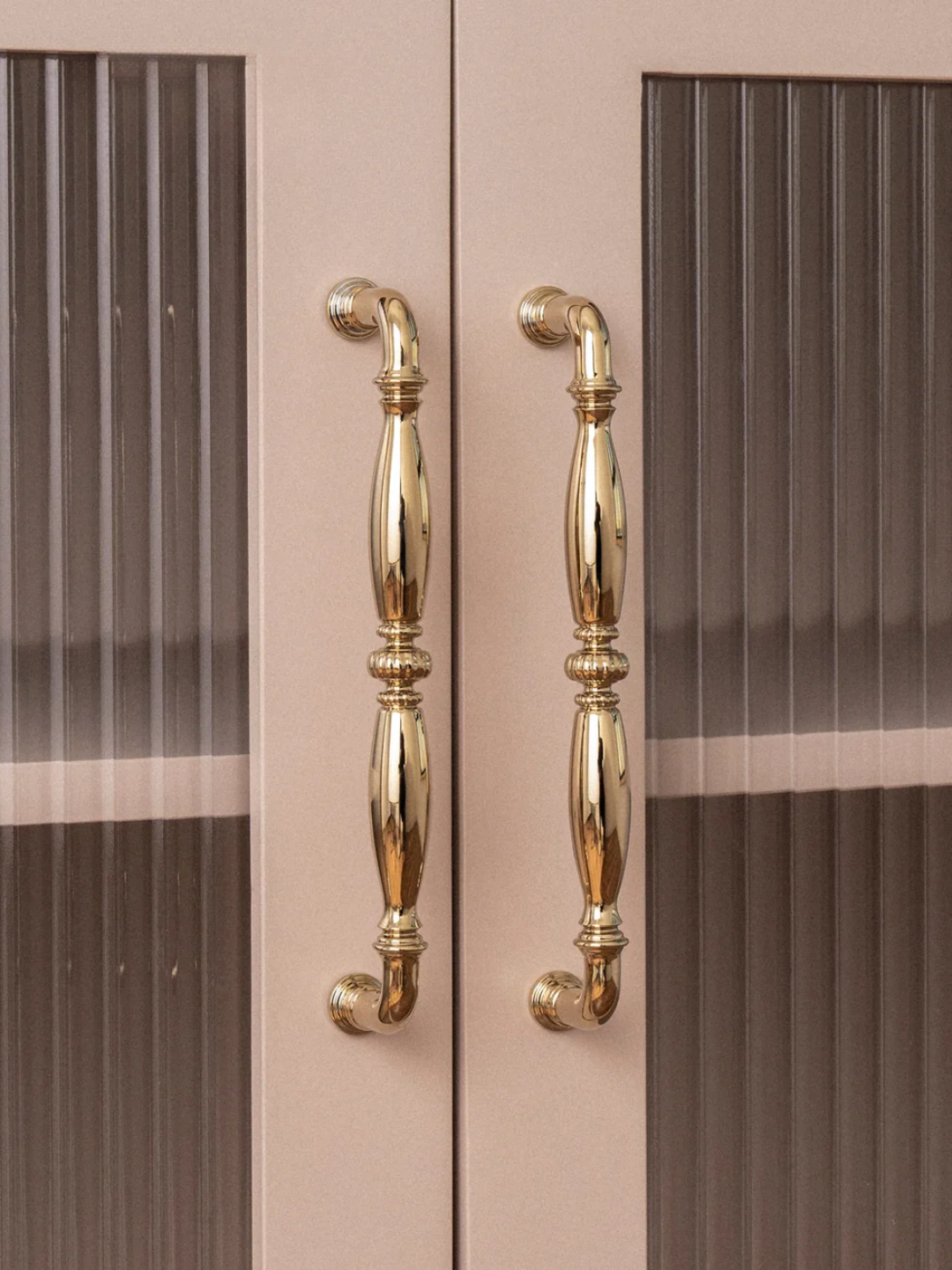 Gold cabinet handles on a pink cabinet with striped pattern