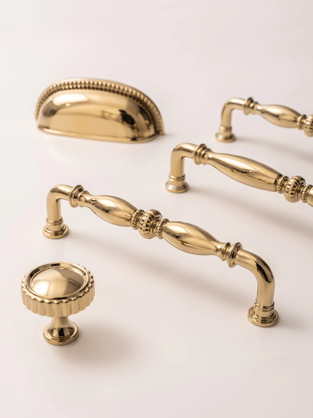 Collection of gold cabinet handles and knobs on a light background