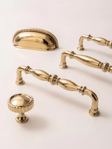 Collection of gold cabinet handles and knobs on a light background