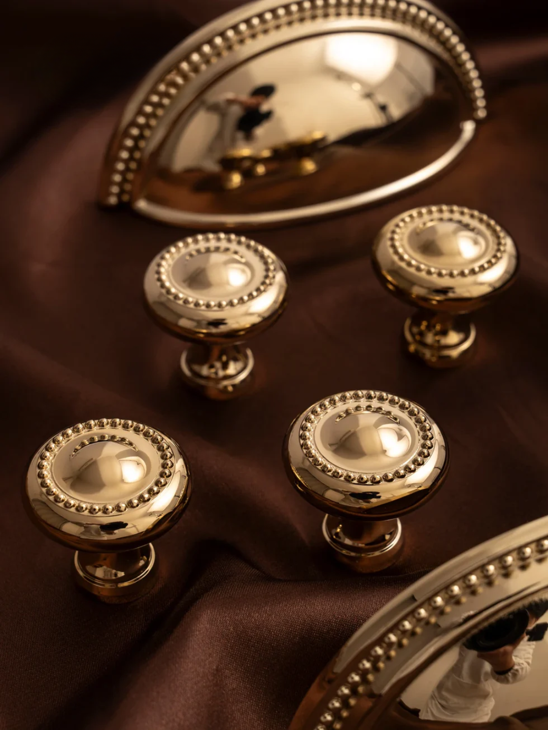 Set of gold cabinet knobs on a brown fabric background