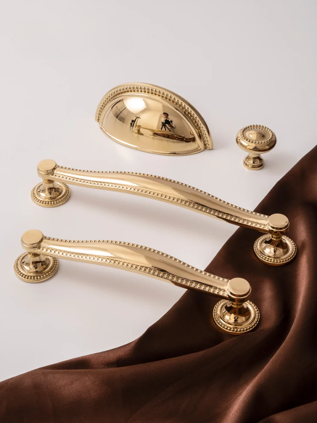 Gold door handles and hardware on a white background with brown fabric.