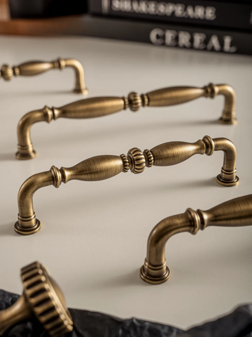 Set of vintage-style brass cabinet handles on a neutral background