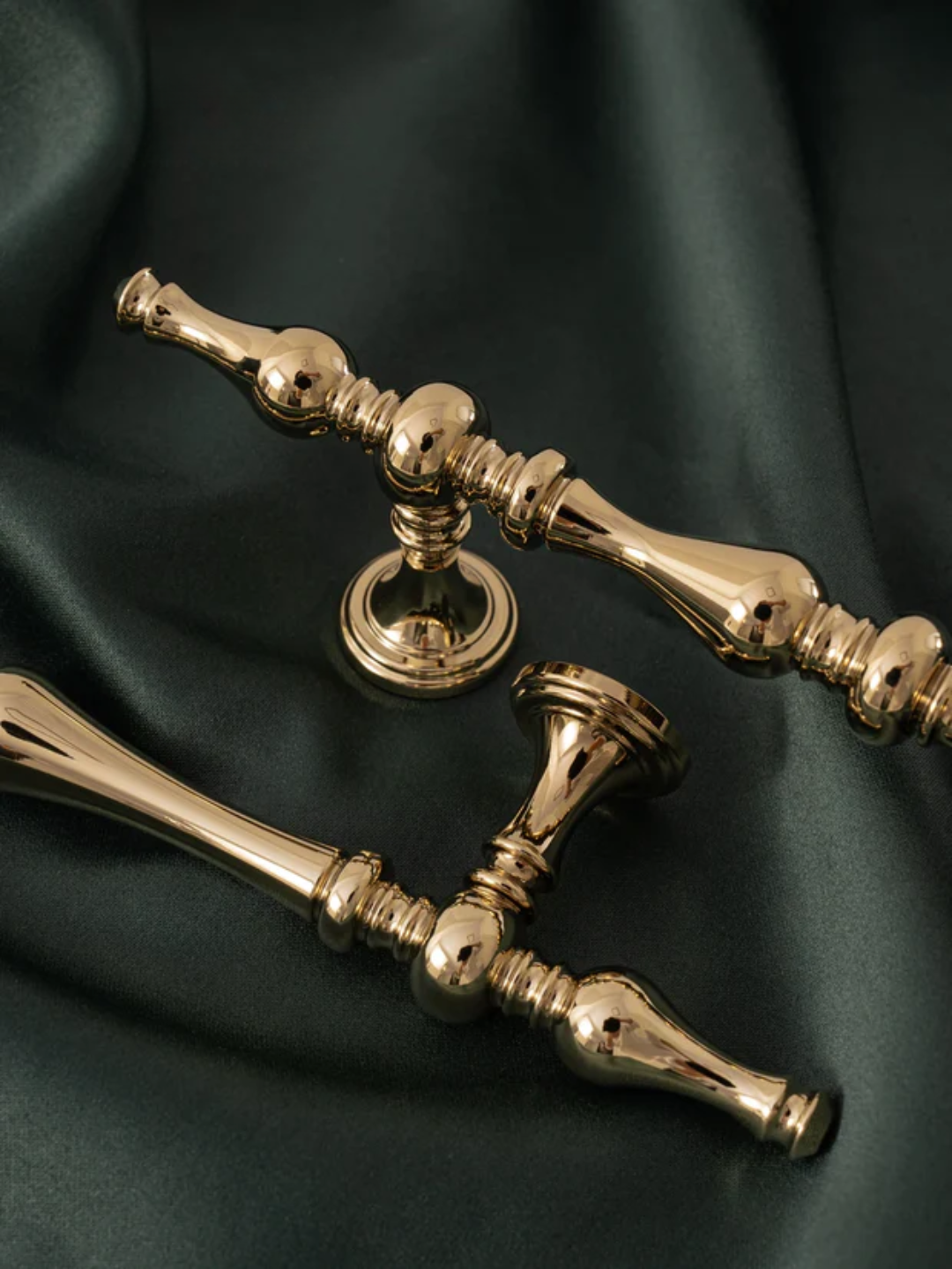 Two gold door handles on a dark green fabric background